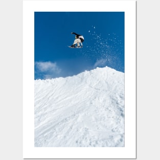 Snowboarder jumping against blue sky Posters and Art